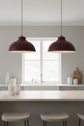 Pair of burgundy pendant shades lit above a pale kitchen island