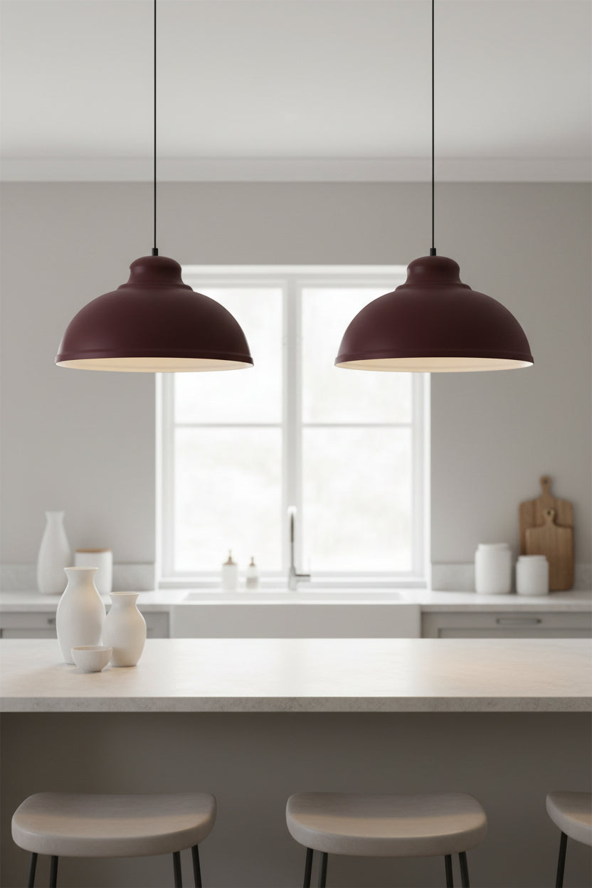 Pair of burgundy pendant shades lit above a pale kitchen island