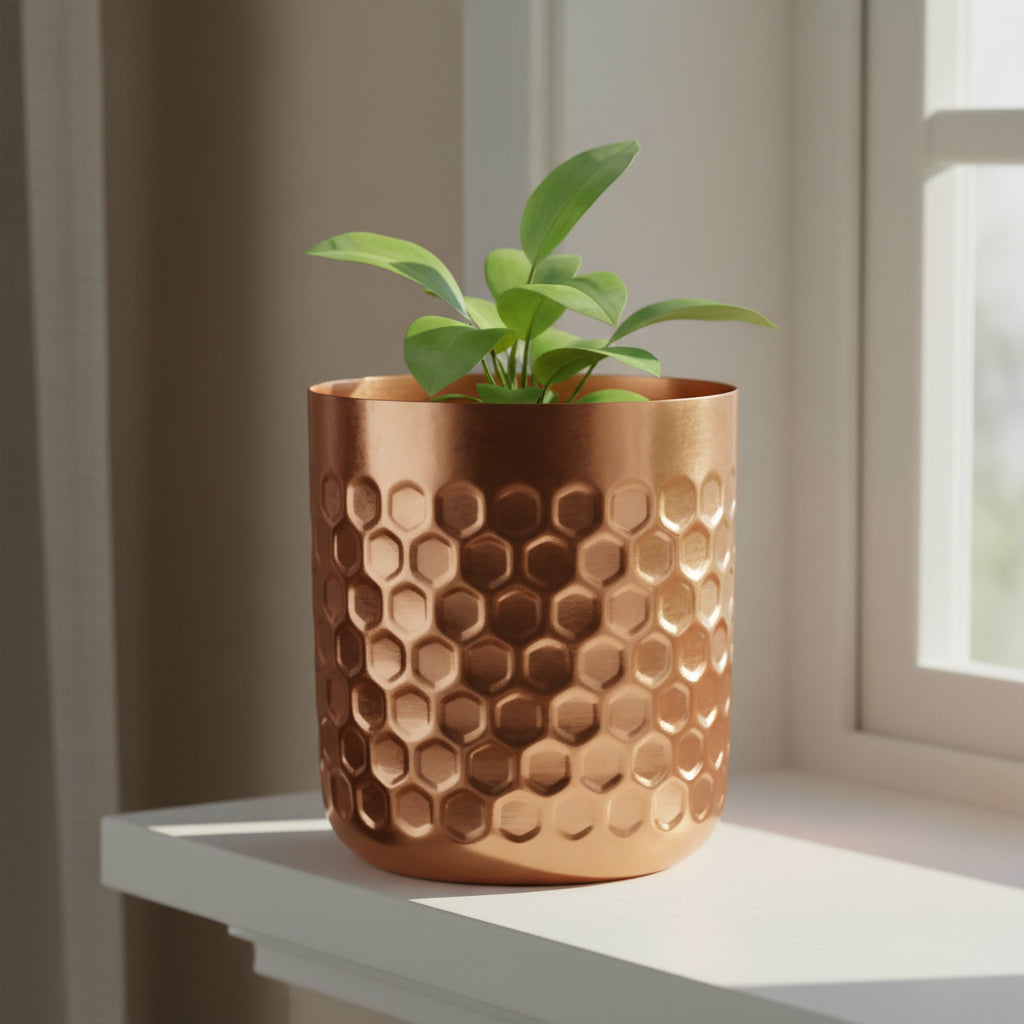 Copper honeycomb metal planter on a painted windowsill in morning light