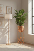 Copper pot on a matching stand holding a leafy plant in a living room corner beside a floor lamp