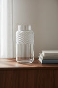 Clear faceted glass vase on a walnut sideboard beside a stack of books