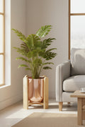 Copper-glazed pot in a bamboo stand holding a leafy plant in a sunlit living room corner