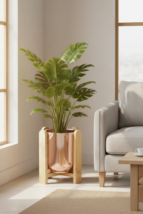 Copper-glazed pot in a bamboo stand holding a leafy plant in a sunlit living room corner