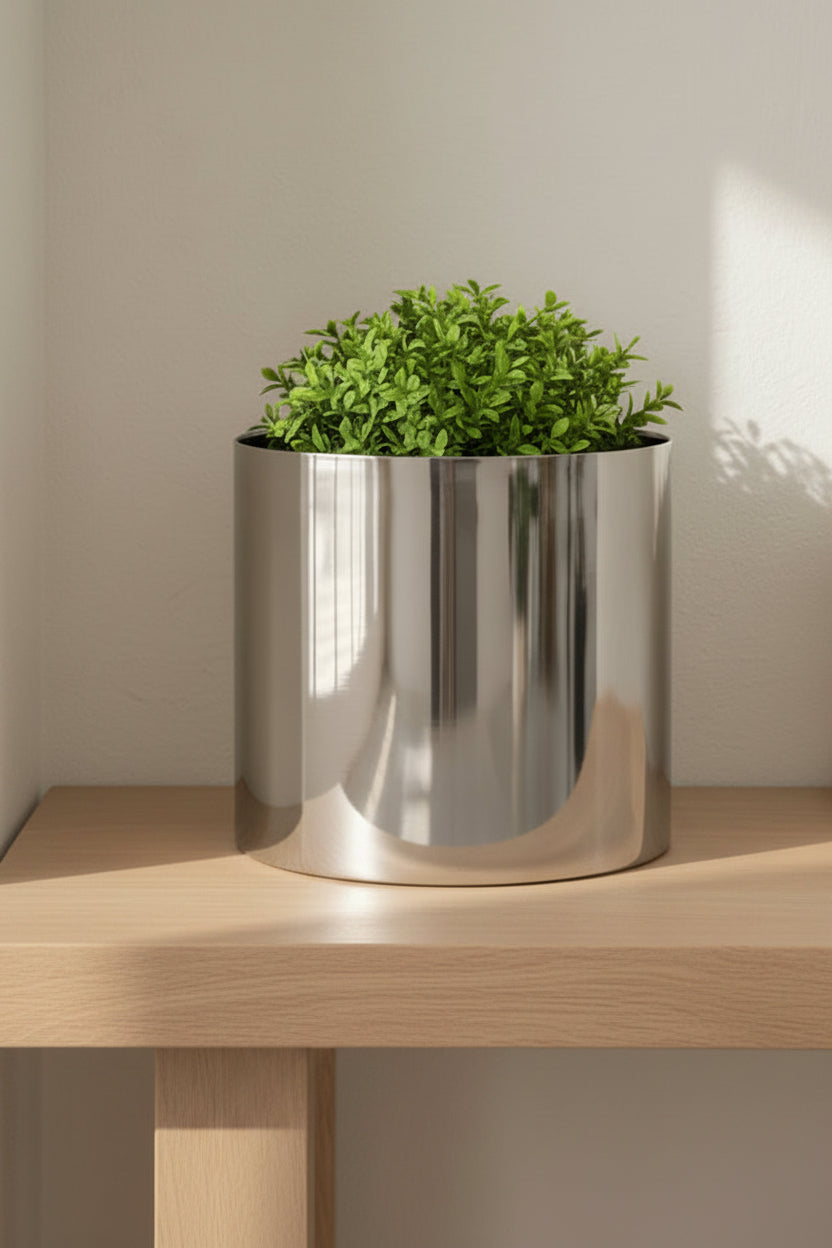 Polished silver planter holding a clipped green plant on a pale oak console table