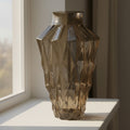 Amber faceted glass vase on a painted windowsill in morning sunlight
