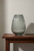 Smoked grey ribbed glass vase on a dark walnut hallway console against a plaster wall