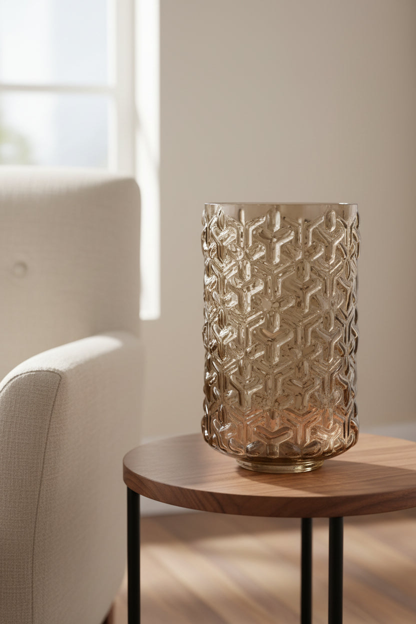 Embossed chestnut glass vase on a walnut side table beside a linen armchair