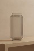 Clear ribbed glass vase on a pale oak console table against a plaster wall