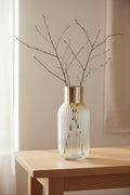 Ridged ombre glass vase holding bare branches on a pale oak console table