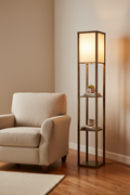 Shelf floor lamp lit in a living room corner beside a linen armchair